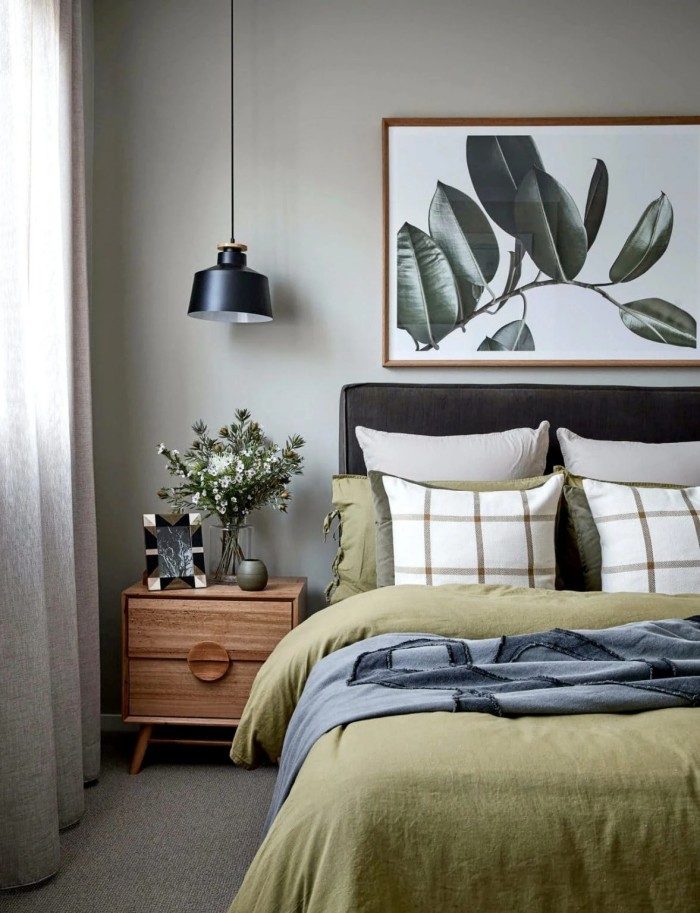 Phòng ngủ màu xanh đất với bộ khăn trải giường màu ô liu tường ô liu và tủ đầu giường bằng gỗ nâu với hoa bản địa